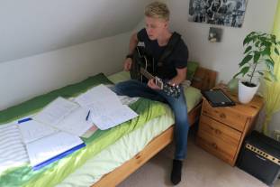Leon Braje auf seinem Bett beim Songschreiben